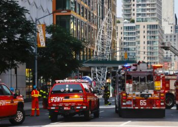 Los bomberos inspeccionan una grúa de construcción que se incendió y colapsó en Nueva York, el 26 de julio de 2023. - El Departamento de Bomberos de la ciudad de Nueva York informó que dos bomberos y al menos cuatro civiles sufrieron heridas leves en el accidente. (Foto de Kena Betancur / AFP)