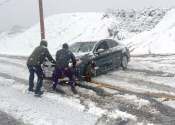 Los residentes locales intentan evitar que un automóvil se deslice por una carretera helada durante una tormenta de nieve en Rancho Cucamonga, California, el 25 de febrero de 2023. Cayeron fuertes nevadas en el sur de California cuando la primera tormenta de nieve en una generación azotó las colinas alrededor de Los Ángeles, con Fuertes lluvias que amenazan con inundaciones en otros lugares. (Foto de JOSH EDELSON / AFP)