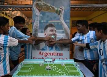 Los miembros del club de aficionados al fútbol argentino celebran el 37 cumpleaños del futbolista argentino Lionel Messi frente a un cartel con su imagen, en Calcuta el 24 de junio de 2024. (Foto de DIBYANGSHU SARKAR / AFP)